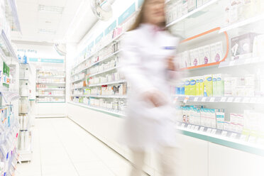 Pharmacist walking in aisle of pharmacy - CAIF14702