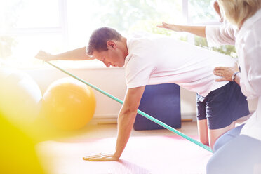 Physical therapist guiding man pulling resistance band - CAIF14753