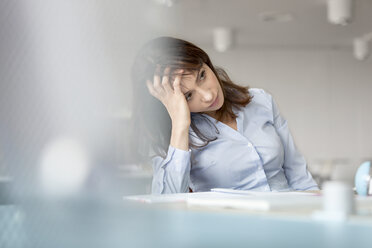 Tired businesswoman with head in hands looking away - CAIF14755