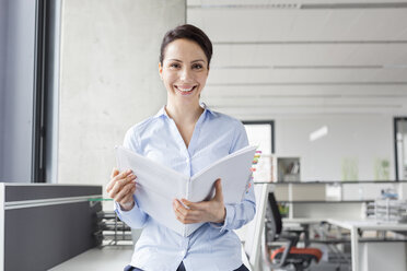 Portrait smiling businesswoman holding report in office - CAIF14758