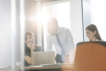 Business people working at laptop in sunny conference room meeting - CAIF14761