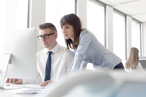 Konzentrierter Geschäftsmann und Geschäftsfrau bei der Arbeit am Computer im Büro, lizenzfreies Stockfoto