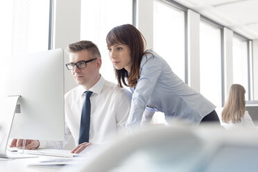 Focused businessman and businesswoman working at computer in office - CAIF14769