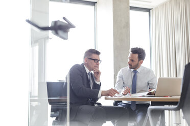 Businessmen reviewing and discussing report in conference room - CAIF14770