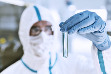 Close up of scientist in clean suit examining sample in test tube - CAIF14792