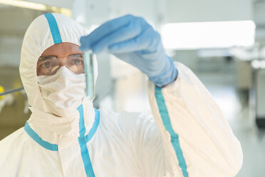 Scientist in clean suit examining sample in test tube in laboratory - CAIF14795