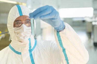 Wissenschaftler im sauberen Anzug untersucht eine Probe im Reagenzglas im Labor - CAIF14795