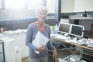 Businesswoman carrying paperwork in office - CAIF14804