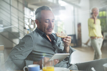 Older man using digital tablet at breakfast table - CAIF14806