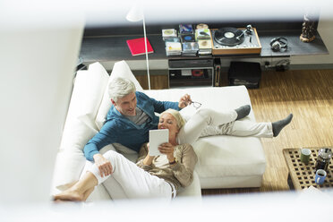 High angle view of older couple using digital tablet on sofa - CAIF14823