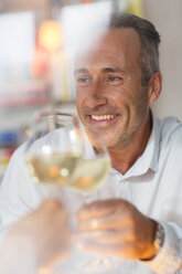 Smiling older man toasting with white wine - CAIF14834