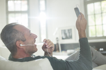 Nahaufnahme eines älteren Mannes mit Ohrstöpseln, der mit einem Mobiltelefon spricht - CAIF14841