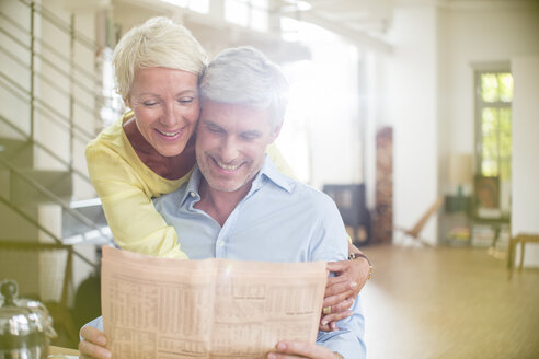 Ältere Frau, die ihren Mann umarmt und Zeitung liest - CAIF14851