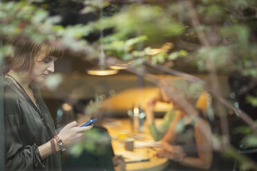 Businesswoman using cell phone in office - CAIF14871