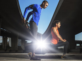 Men stretching before exercising on city street - CAIF14933