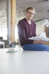 Businessman reading paperwork in office - CAIF14966