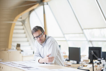 Businessman reading paperwork at office desk - CAIF14976