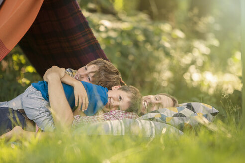 Vater und Söhne entspannen zusammen in der Nähe des Campingzeltes - CAIF14981