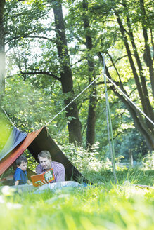 Vater und Sohn lesen im Campingzelt - CAIF14986