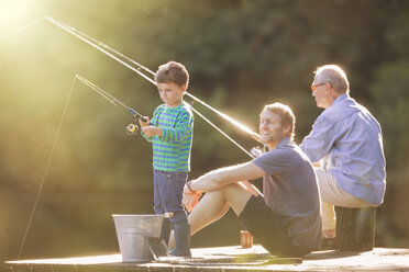 Boy, father and grandfather fishing on wooden dock - CAIF14998