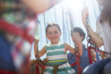 Girl smiling on carousel in amusement park - CAIF15016