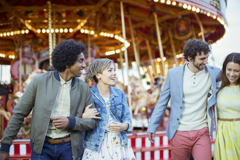 Zwei Paare, die im Vergnügungspark spazieren gehen und lachen, lizenzfreies Stockfoto