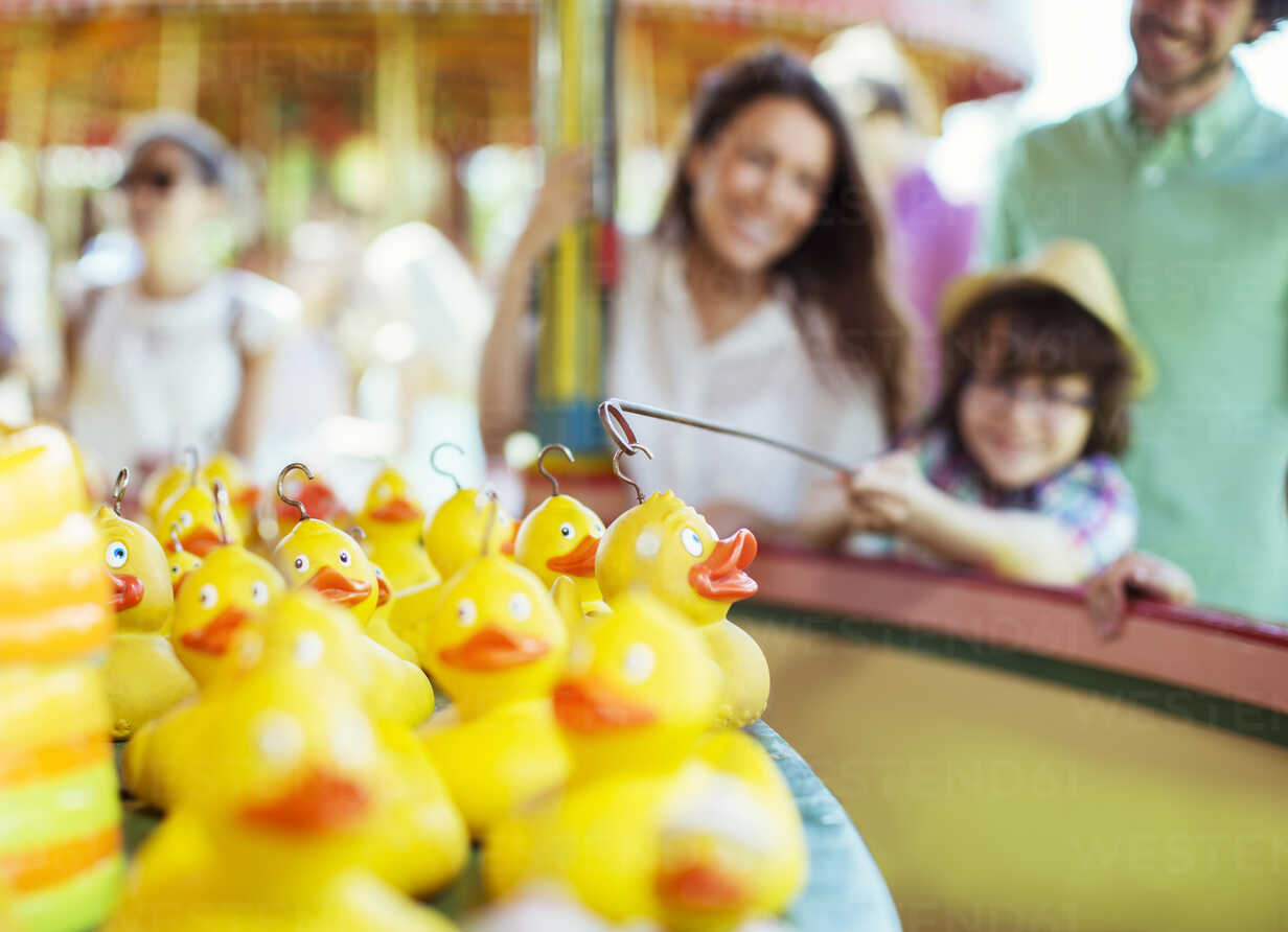 Boy trying to catch rubber duck on fishing game in amusement park stock  photo