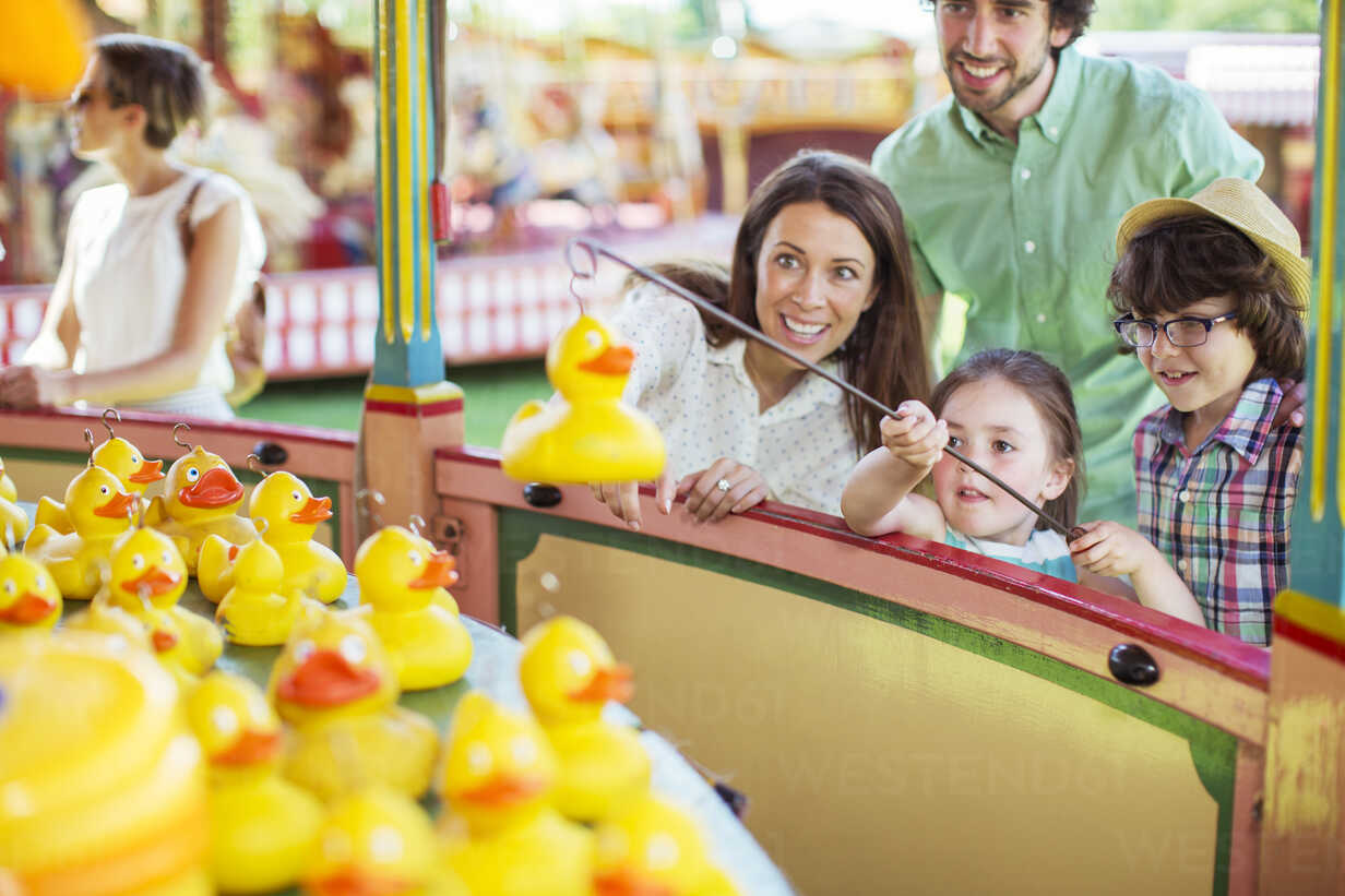 Parents with two children having fun with fishing game in amusement park  stock photo