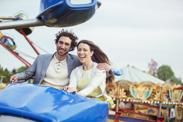 Couple enjoying ride on carousel in amusement park - CAIF15032