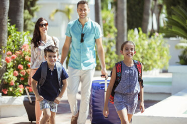 Family with suitcases walking towards tourist resort - CAIF15067