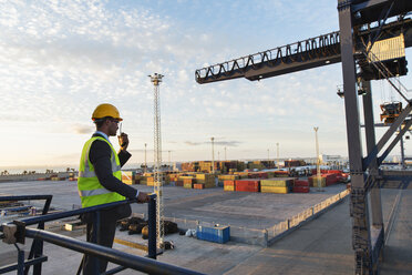 Worker using walkie-talkie near crane - CAIF15079
