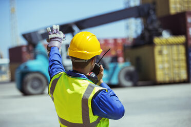 Arbeiter benutzt Walkie-Talkie in der Nähe von Frachtcontainern - CAIF15088