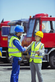 Geschäftsfrau und Arbeiter schütteln sich in der Nähe von Lastwagen die Hände - CAIF15092