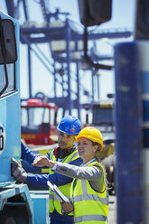 Businesswoman and worker examining truck near cargo crane - CAIF15101