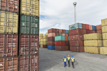 Businessmen and worker walking near cargo containers - CAIF15102