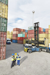 Businessmen and worker talking near cargo containers - CAIF15106