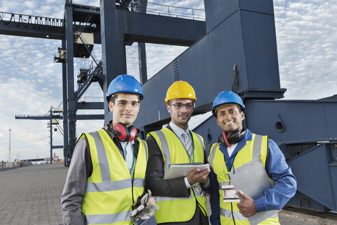 Workers and businessman smiling near cargo crane - CAIF15121