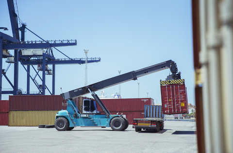 Kran hebt Frachtcontainer auf Lastwagen, lizenzfreies Stockfoto