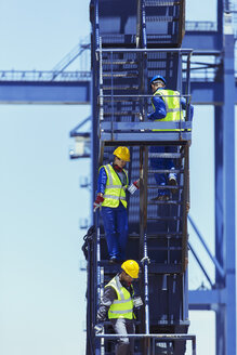 Geschäftsmann und Arbeiter klettern Treppe auf Frachtkran - CAIF15129