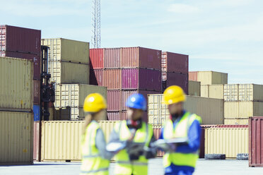 Businessman and workers talking near cargo containers - CAIF15131