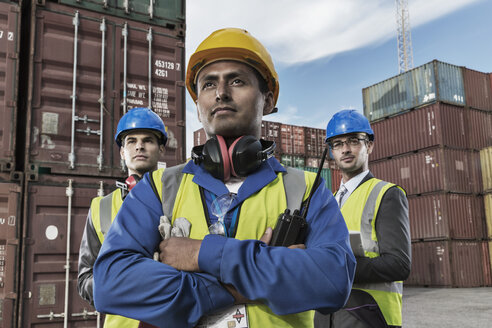 Worker and businessmen standing near cargo containers - CAIF15140