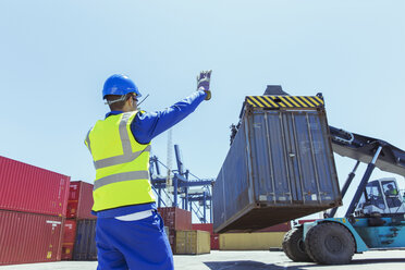 Arbeiter, der einen Kran mit einem Frachtcontainer steuert - CAIF15148