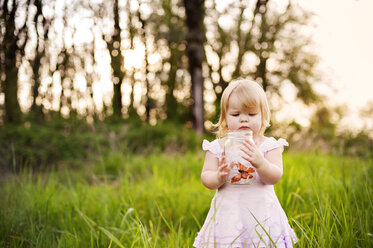 Cute girl looking at butterfly in jar - CAVF06066