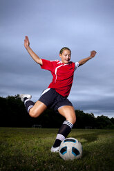 Teenage girl kicking soccer ball while playing soccer - CAVF06101