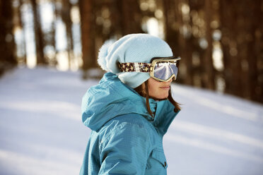 Frau mit Skibrille steht auf einem verschneiten Feld - CAVF06171