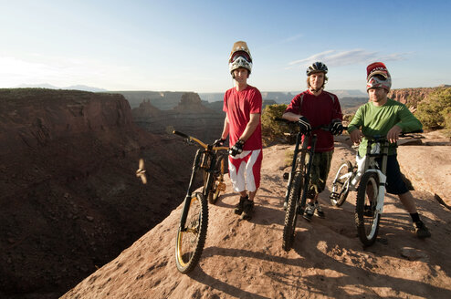 Porträt von Mountainbikern mit Fahrrädern, die auf einer Klippe stehen - CAVF06188