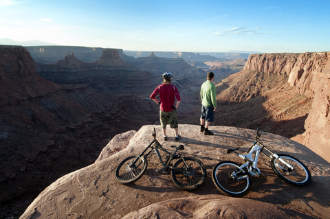 Rückansicht von Mountainbikern, die auf einem Felsen stehen, lizenzfreies Stockfoto