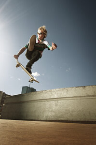 Niedriger Blickwinkel von Mann springt mit Skateboard gegen den Himmel - CAVF06244