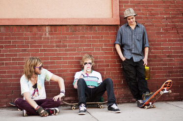 Freunde mit Skateboard, die sich an einer Mauer ausruhen - CAVF06251