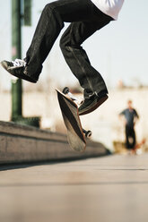 Niedriger Ausschnitt eines Mannes, der mit einem Skateboard auf einen Fußweg springt - CAVF06258
